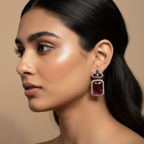Elegant stud earrings with cushion-cut ruby and diamond accents, set in a vintage floral design, displayed on a textured beige stone platform.