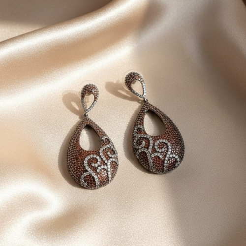 Elegant brown and silver teardrop zircon earrings on copper base displayed on satin fabric